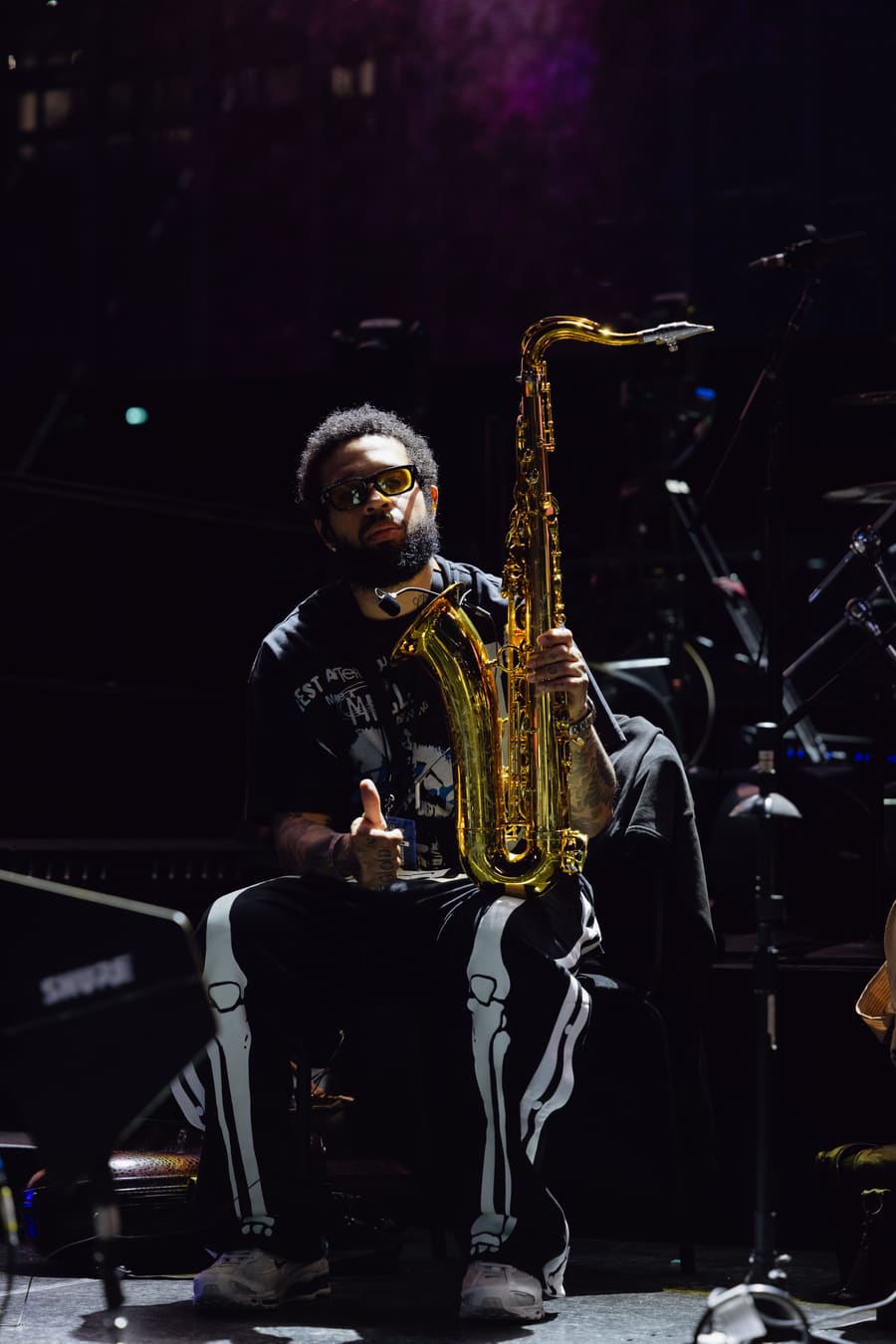 Kenneth Whalum on stage in amber light, holding a gold tenor saxophone